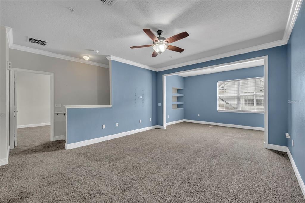 A carpeted living room features blue walls, a ceiling fan, and a recessed window area — 200 SOUTHERN PECAN CIRCLE UNIT 206, WINTER GARDEN, FL