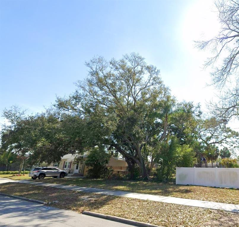 A large tree shades a house and a white fence along a sidewalk — 000 16TH AVENUE N, ST PETERSBURG, FL