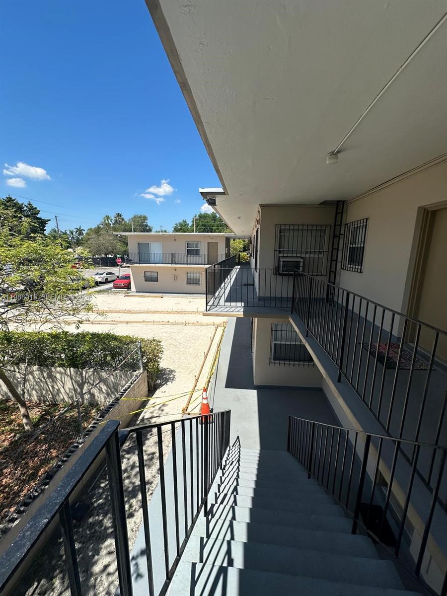 An exterior view of an apartment building showing a staircase, walkway, and sandy ground — 100 NE 78th St # 4, Miami FL 33138, MIAMI, FL