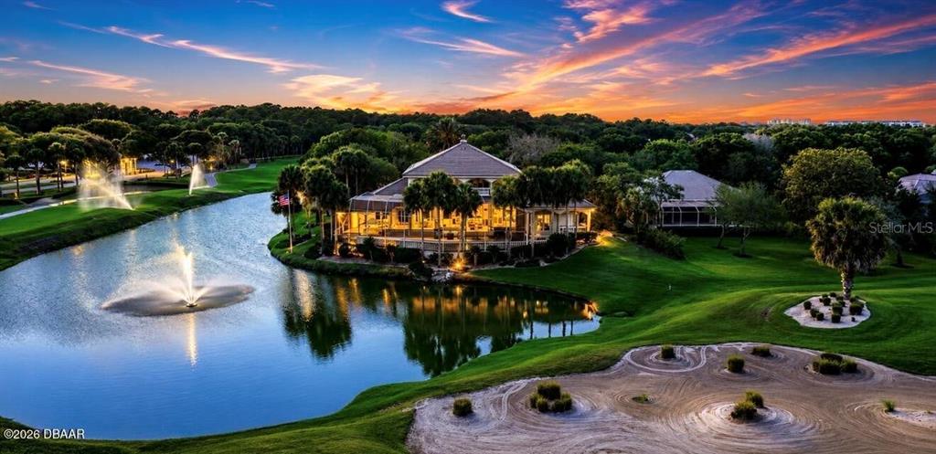 An aerial view shows a house beside a pond with a fountain and golf course — 25 SAN MARCO COURT, PALM COAST, FL