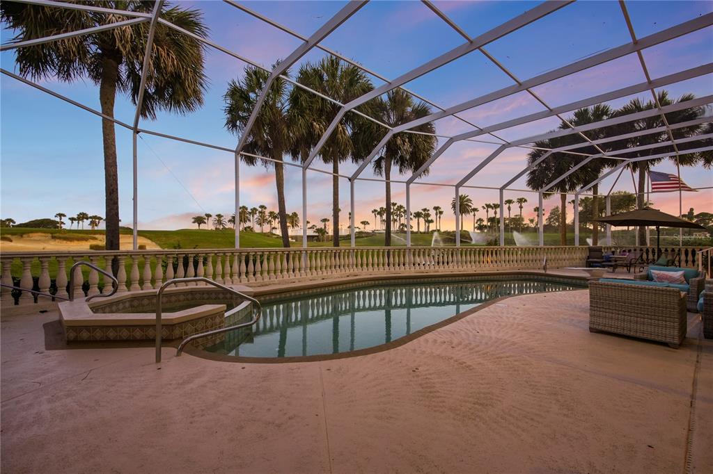 A screened-in pool and hot tub overlook a golf course at sunset — 25 SAN MARCO COURT, PALM COAST, FL