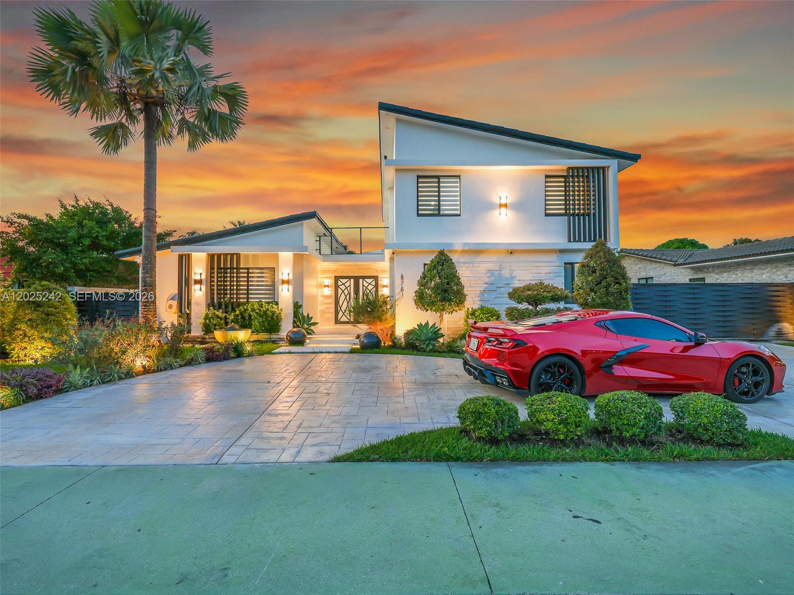A modern two-story house with a red sports car parked on the driveway at sunset — 8761 SW 56th St, Miami FL 33165, MIAMI, FL