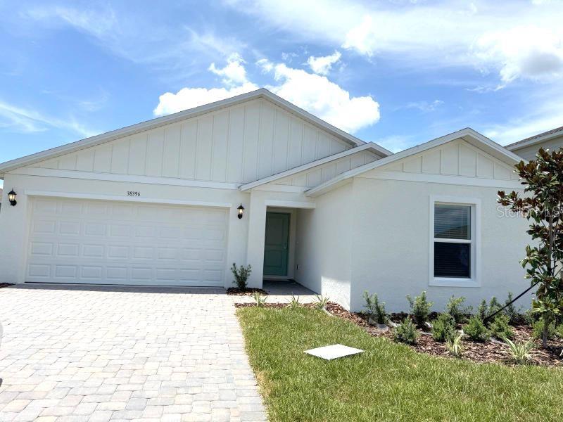 A single-story house with a white exterior, a two-car garage, and a paved driveway — 38396 PINDOS DRIVE, DADE CITY, FL