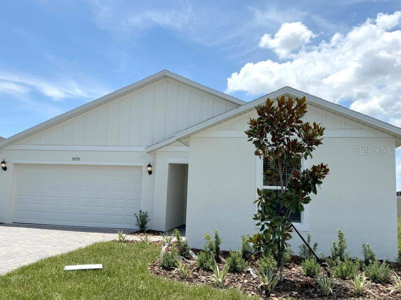 A single-story house with a white exterior, a two-car garage, and a small front garden — 38396 PINDOS DRIVE, DADE CITY, FL