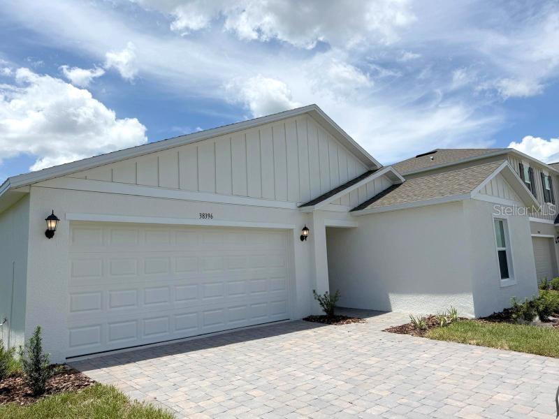A single-story house with a white stucco exterior, a two-car garage, and a paver driveway — 38396 PINDOS DRIVE, DADE CITY, FL