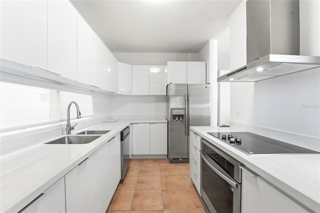 A modern kitchen features white cabinets, stainless steel appliances, and light-colored countertops — 115 PASEO REAL, DORADO, PR