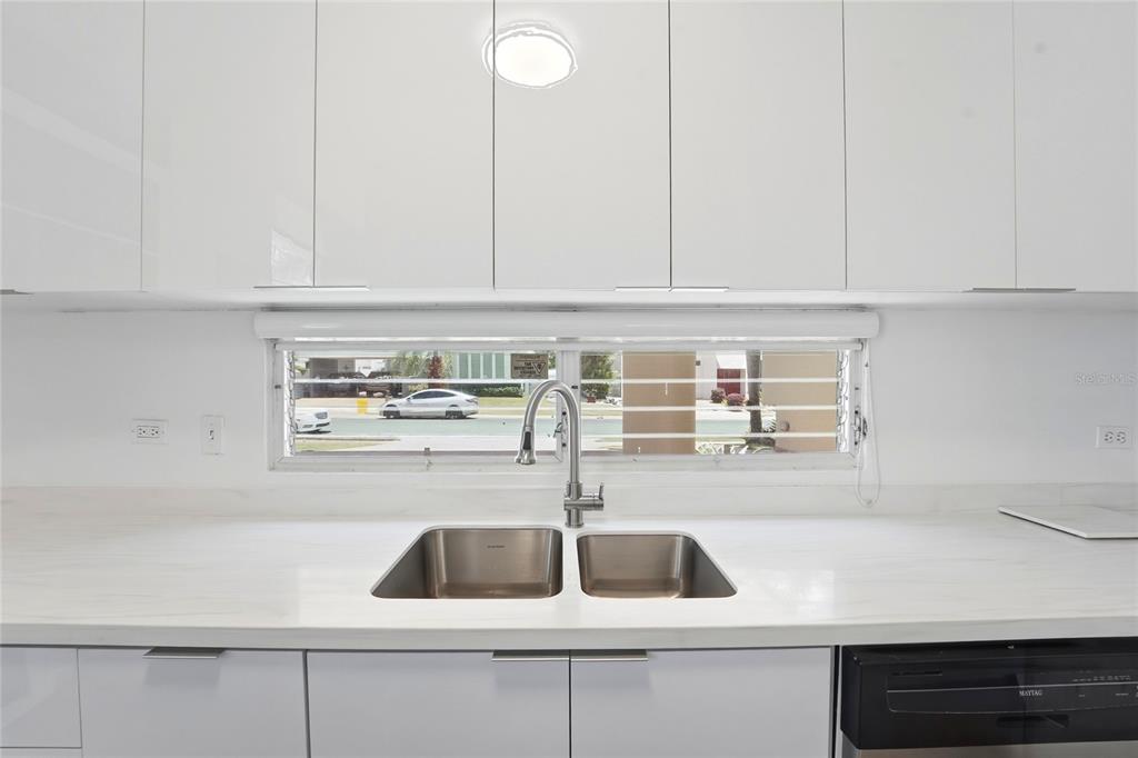 A kitchen sink with a stainless steel faucet sits below a window in a white kitchen — 115 PASEO REAL, DORADO, PR