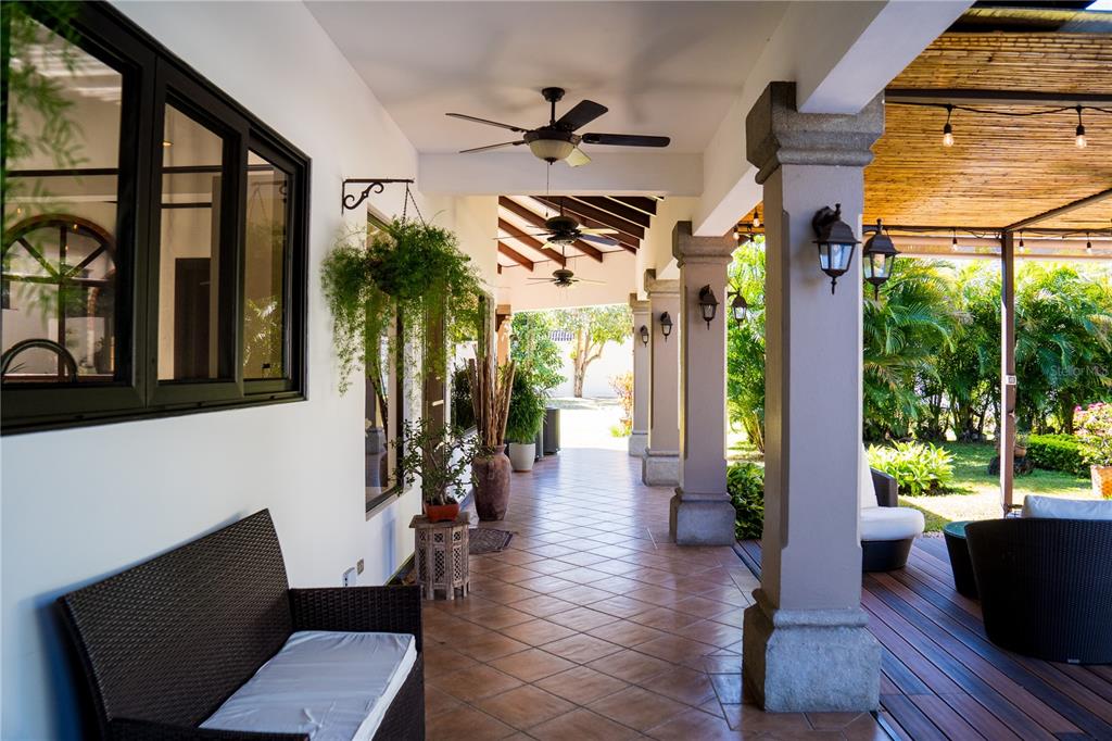 A covered outdoor patio features tiled flooring, ceiling fans, stone columns, and wicker furniture — 84 URBANIZACION DE RIO ORO, SANTA ANA, OC
