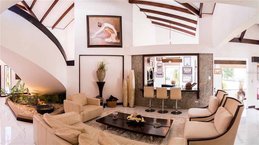 A living room features a curved staircase, a built-in bar, and cream-colored furniture — 84 URBANIZACION DE RIO ORO, SANTA ANA, OC