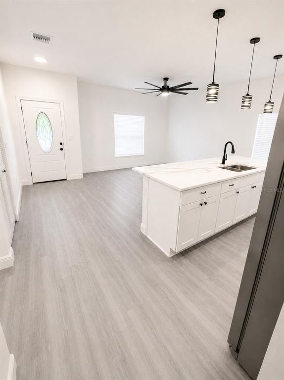 A kitchen with a white island and pendant lights opens into a living area — 545 N LINCOLN STREET, DAYTONA BEACH, FL