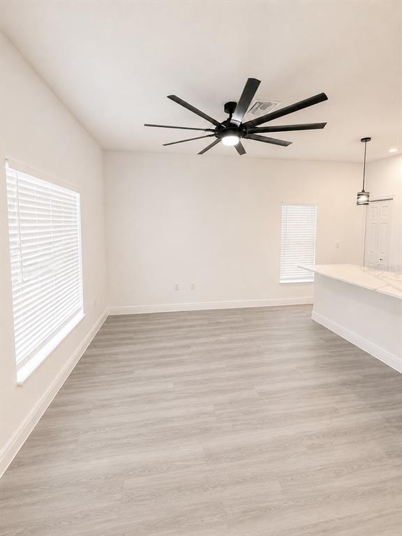A room with light wood-look flooring, white walls, a ceiling fan, and a kitchen island — 545 N LINCOLN STREET, DAYTONA BEACH, FL