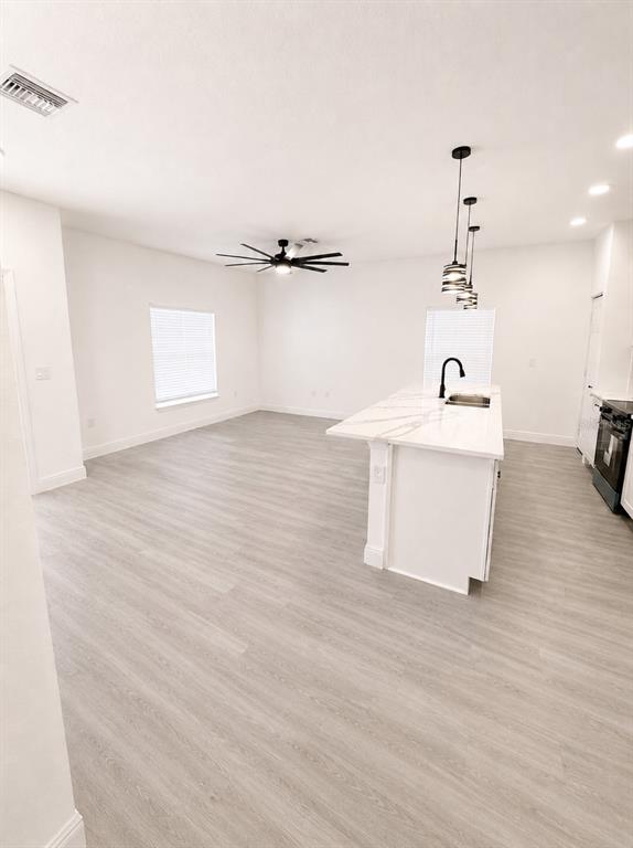 A bright, open-concept kitchen and living area featuring light wood floors and a marble island — 545 N LINCOLN STREET, DAYTONA BEACH, FL