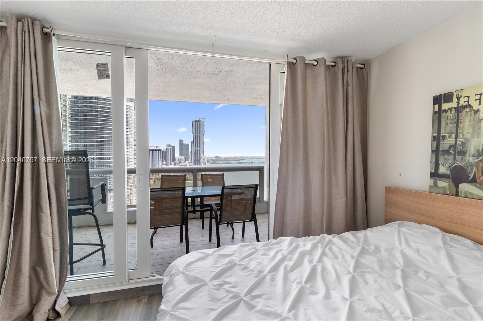 A bedroom with a white bed and sliding glass doors opening to a balcony with views — 1717 N Bayshore Dr # 2837, Miami FL 33132, MIAMI, FL