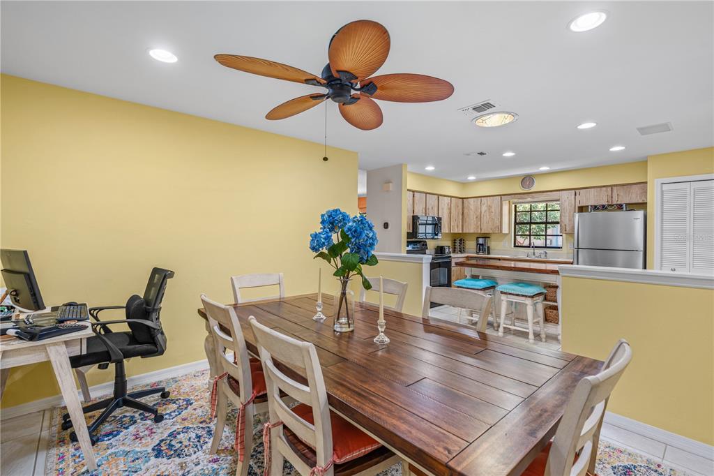 A dining area with a wooden table, chairs, and a desk sits before an open kitchen — 4523 NETTLE CREEK COURT, PORT ORANGE, FL
