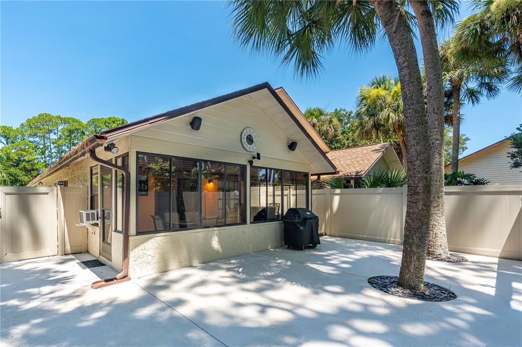 A sunroom with large windows sits on a concrete patio next to palm trees — 4523 NETTLE CREEK COURT, PORT ORANGE, FL