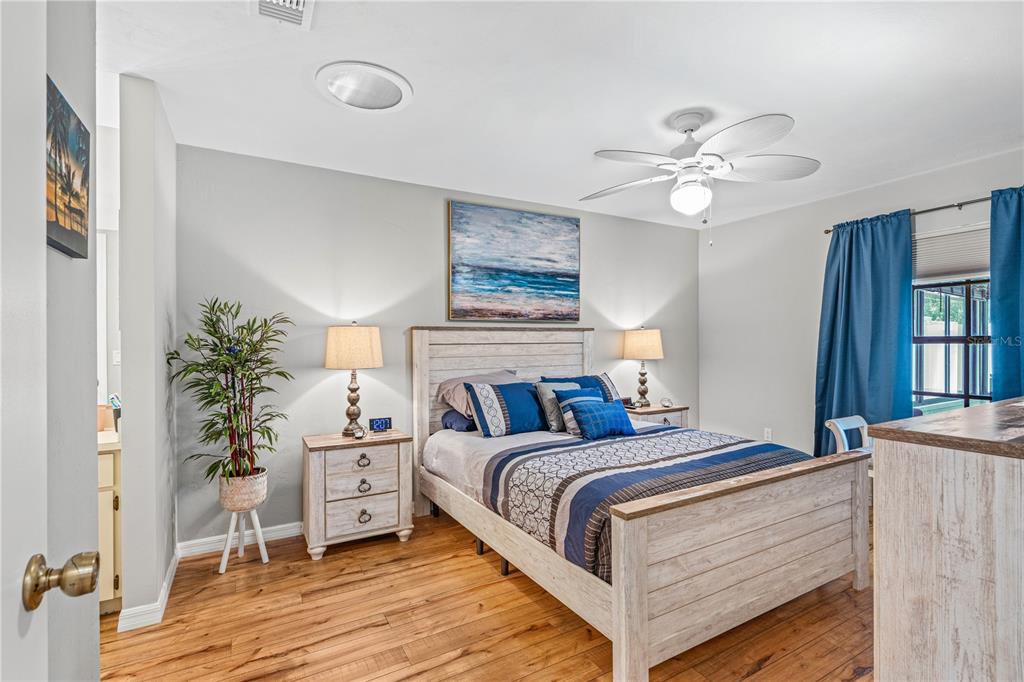 A bedroom features a wooden bed frame, blue accents, and light-colored wood flooring — 4523 NETTLE CREEK COURT, PORT ORANGE, FL