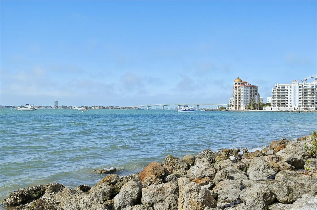 A rocky shoreline overlooks a bay with boats, a bridge, and waterfront buildings — 1771 RINGLING BOULEVARD UNIT 1001, SARASOTA, FL
