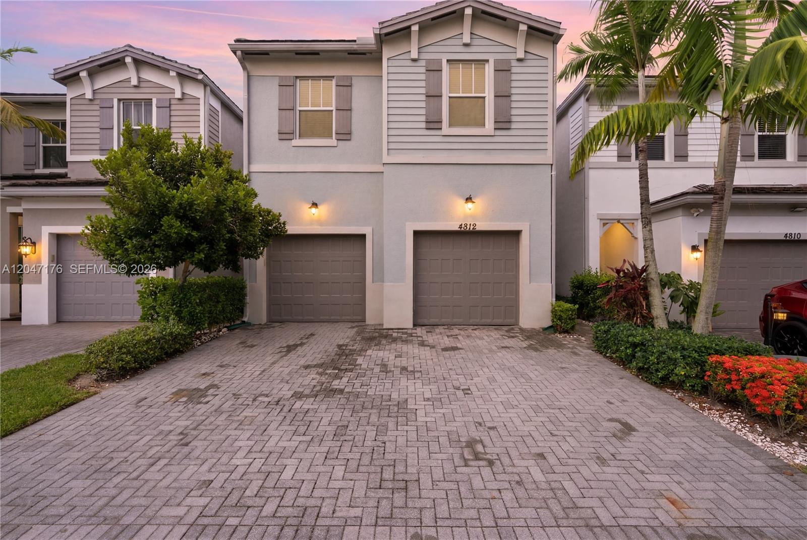 A two-story house with a paved driveway and two garage doors at dusk — 4812 NW 48th Ter, Tamarac FL 33319, TAMARAC, FL