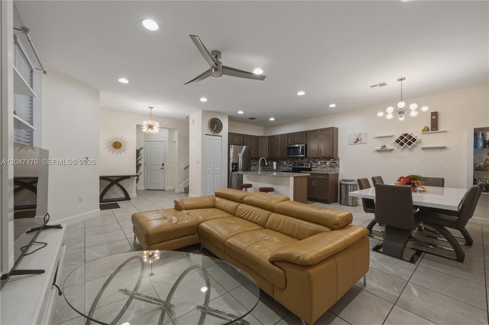 This open-concept living and dining area features tile flooring, a leather sectional, and dark cabinetry — 4812 NW 48th Ter, Tamarac FL 33319, TAMARAC, FL