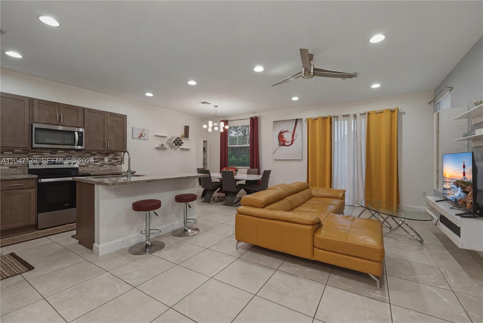 An open-concept living area features a kitchen with an island, dining space, and leather sofa — 4812 NW 48th Ter, Tamarac FL 33319, TAMARAC, FL