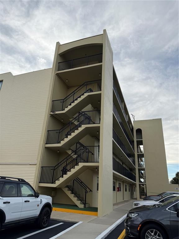 An exterior view of a multi-story apartment building featuring an open-air metal staircase — 1437 N ATLANTIC AVENUE UNIT 410, DAYTONA BEACH, FL