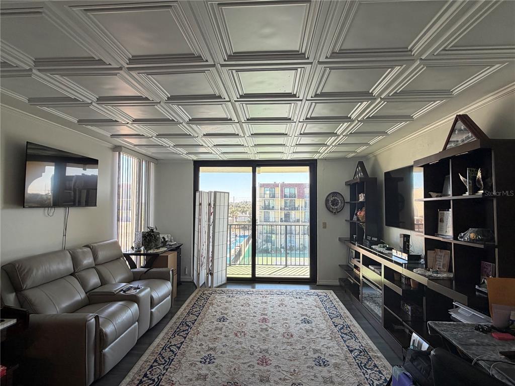 A living room features a coffered ceiling, a beige leather sofa, and a sliding glass door — 1437 N ATLANTIC AVENUE UNIT 410, DAYTONA BEACH, FL