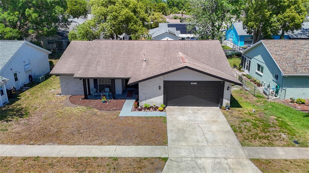 An aerial view shows a single-story house with a brown roof, brick facade, and driveway — 8617 STONEHEDGE WAY, HUDSON, FL
