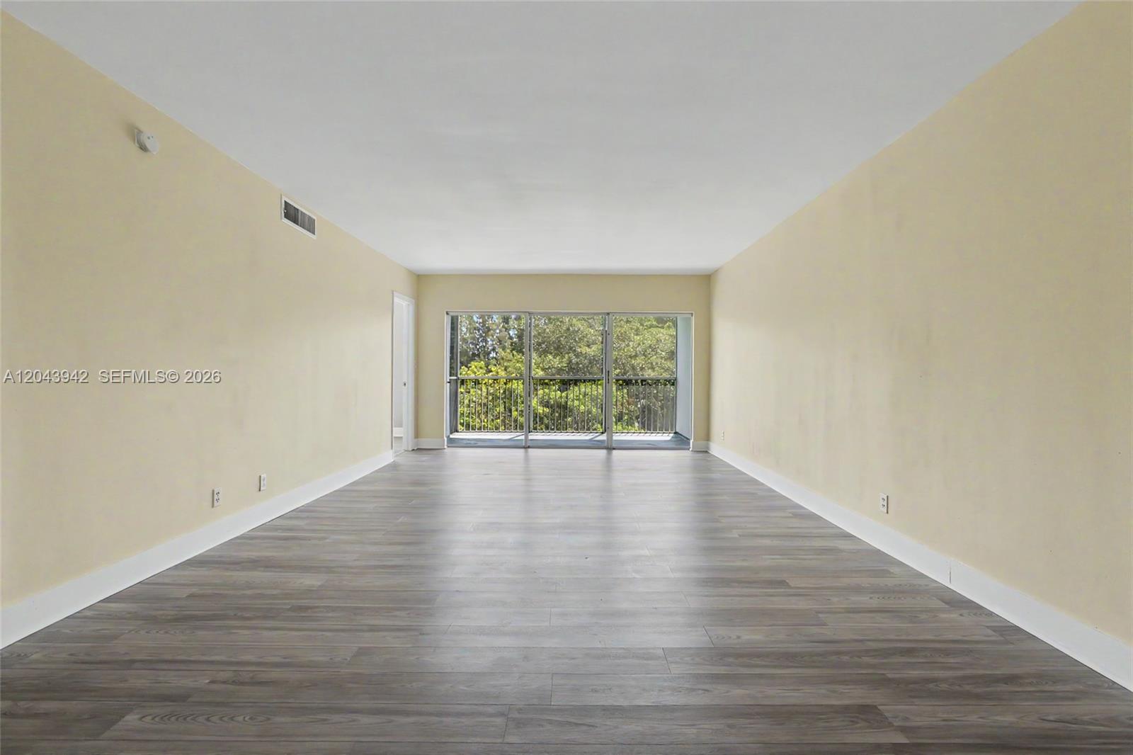 This living room features light wood flooring, a neutral sofa, a round coffee table, and a balcony — 3250 N Palm Aire Dr # 406, Pompano Beach FL 33069, POMPANO BEACH, FL