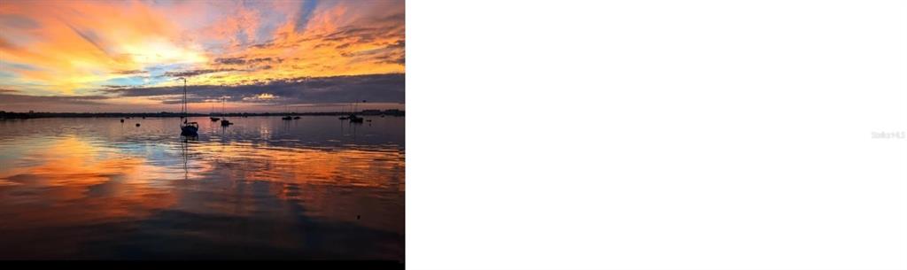 A sunset view over a calm body of water with several sailboats anchored in the distance — 6100 GULFPORT BOULEVARD S UNIT 401, GULFPORT, FL