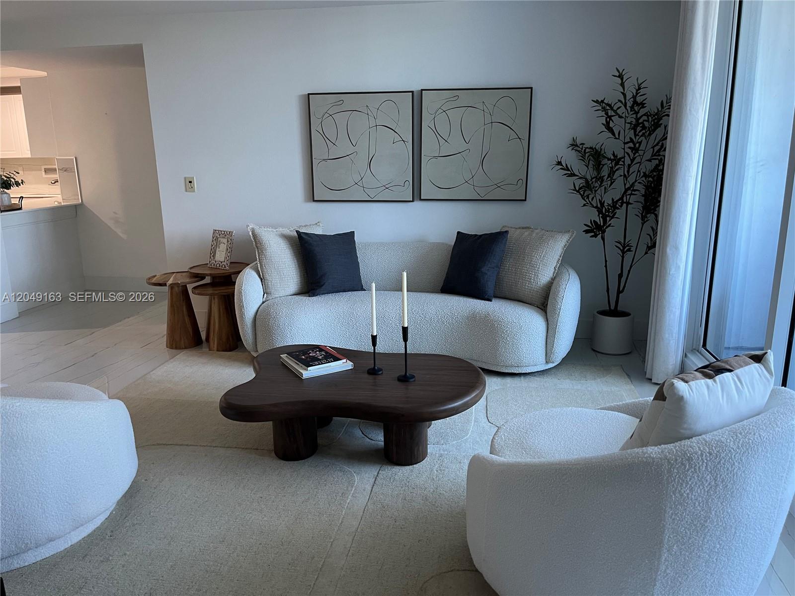 A living room features a curved sofa, two armchairs, and a dark wood coffee table — 2301 Collins Ave # 326, Miami Beach FL 33139, MIAMI BEACH, FL