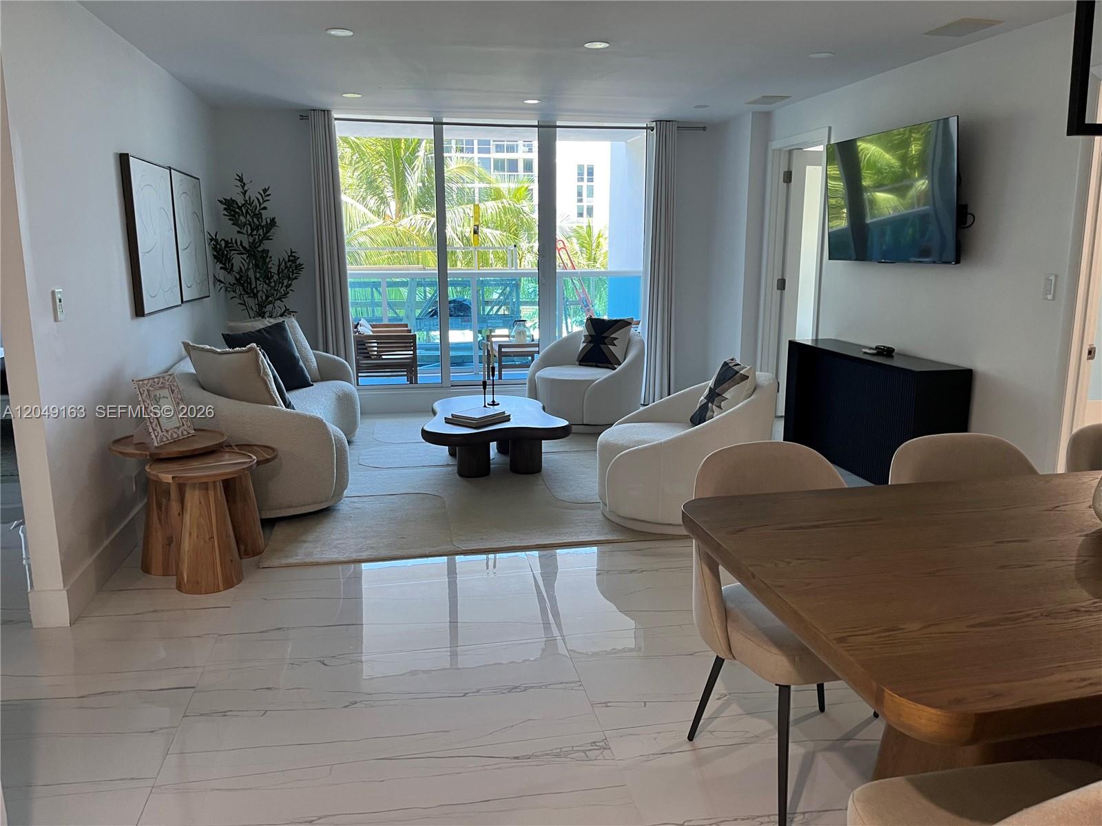 A bright living and dining area features white tiled floors, modern furniture, and a balcony — 2301 Collins Ave # 326, Miami Beach FL 33139, MIAMI BEACH, FL