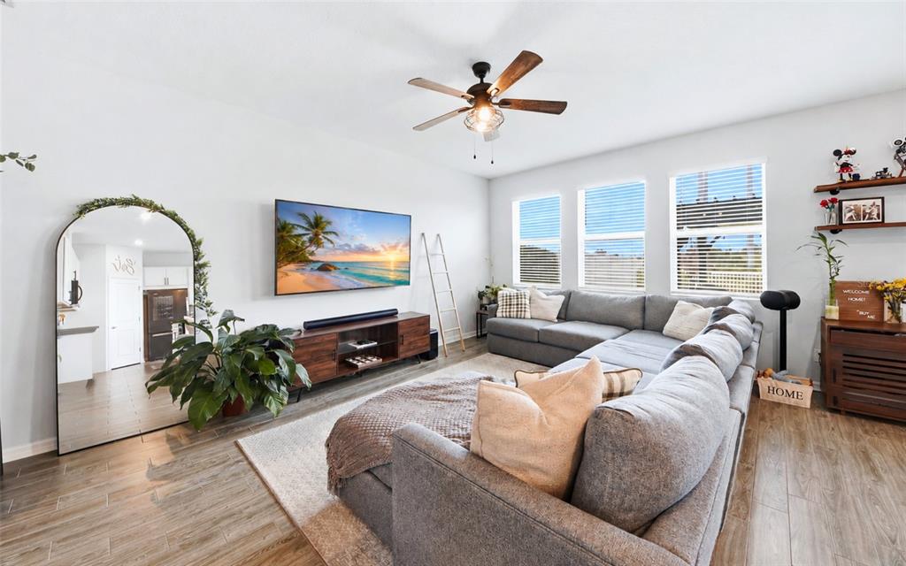 A living room features a gray sectional sofa, a wall-mounted television, and a large arched mirror — 11873 BRIGHTON KNOLL LOOP, RIVERVIEW, FL