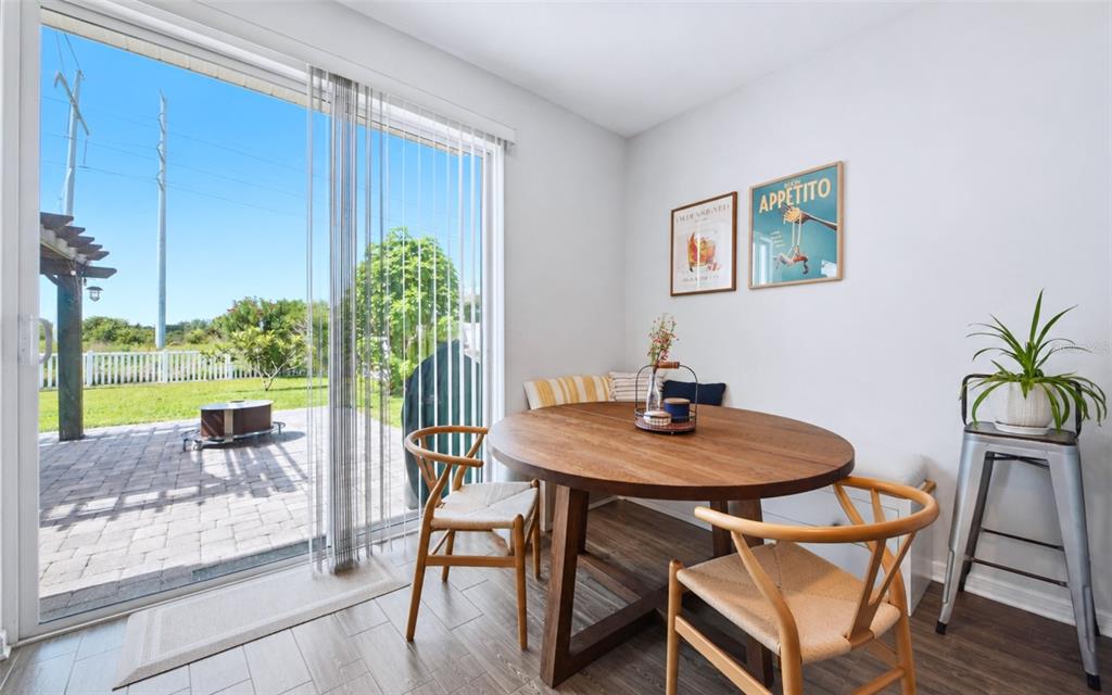 A dining area features a round wooden table, chairs, bench seating, and a sliding glass door — 11873 BRIGHTON KNOLL LOOP, RIVERVIEW, FL