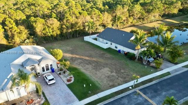 An aerial view shows a vacant residential lot situated between two houses and a pond — 1570 SW 16th Ct SW, Vero Beach FL 32962, VERO BEACH, FL
