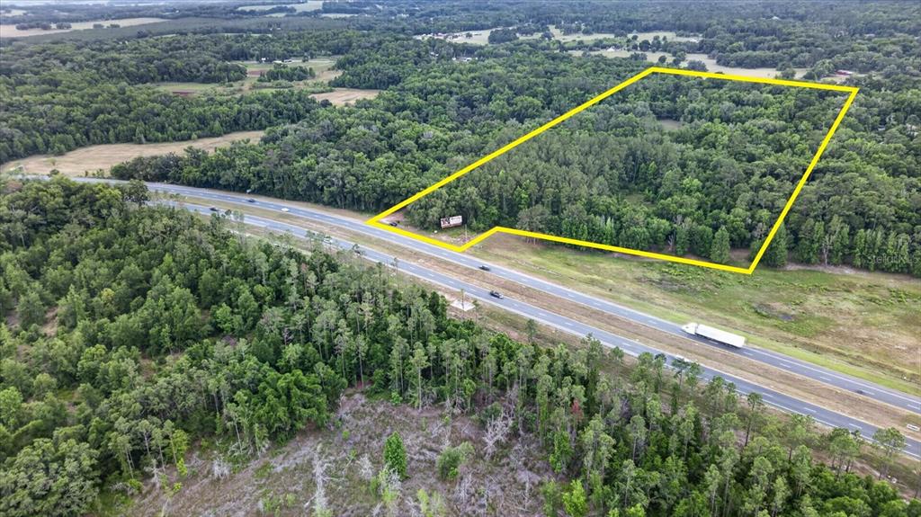 An aerial view shows a wooded plot of land outlined in yellow beside a highway — 0 CORTEZ BLVD, BROOKSVILLE, FL