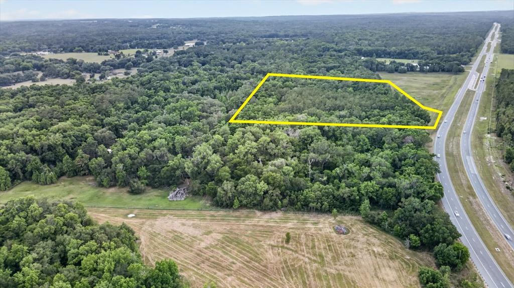 An aerial view shows a wooded lot outlined in yellow adjacent to a divided highway — 0 CORTEZ BLVD, BROOKSVILLE, FL