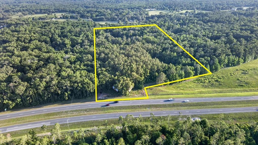 An aerial view shows a wooded plot of land outlined in yellow beside a highway — 0 CORTEZ BLVD, BROOKSVILLE, FL