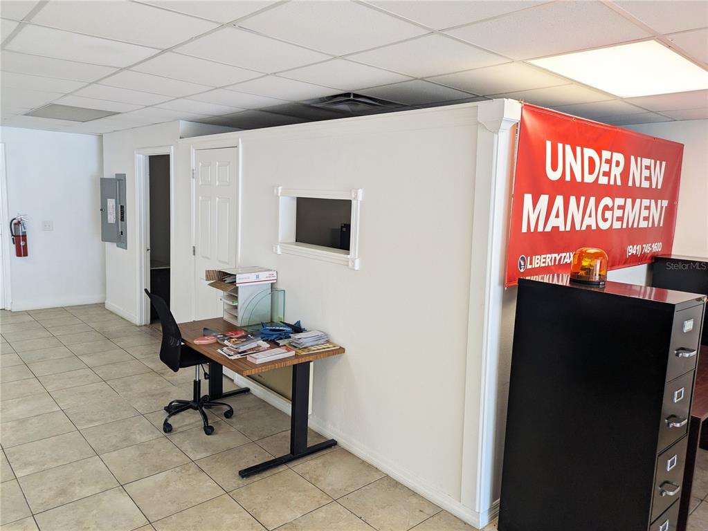 An office interior features a desk, a partition wall with a window, and a banner — 837 8TH AVENUE W UNIT 837, PALMETTO, FL
