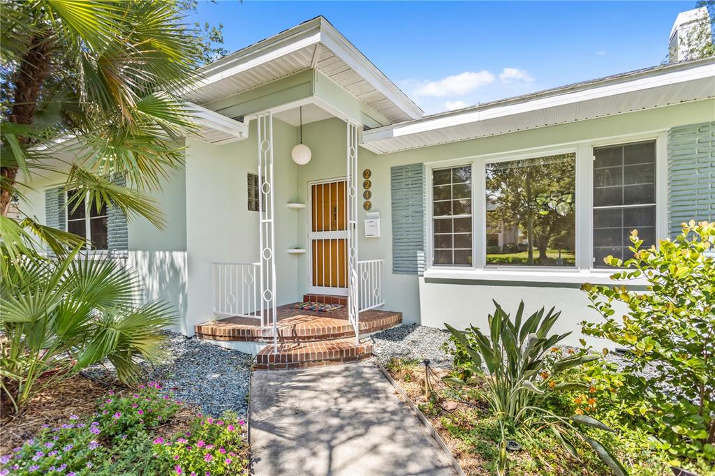 A light green house features a brick porch, white metal railings, and a front door — 2217 BREVARD ROAD NE, ST PETERSBURG, FL