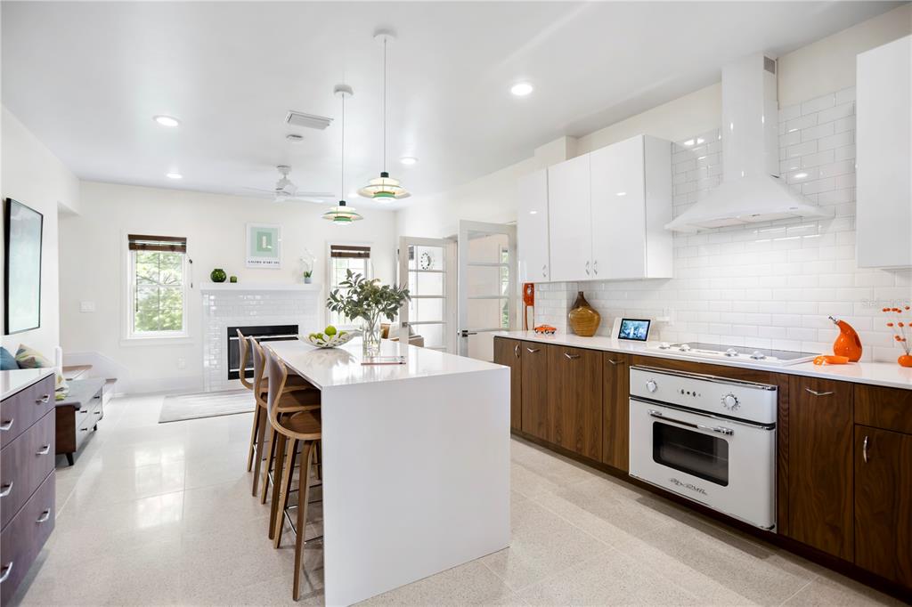 A modern kitchen features a white island, wood-toned lower cabinets, white upper cabinets, and tile flooring — 2217 BREVARD ROAD NE, ST PETERSBURG, FL