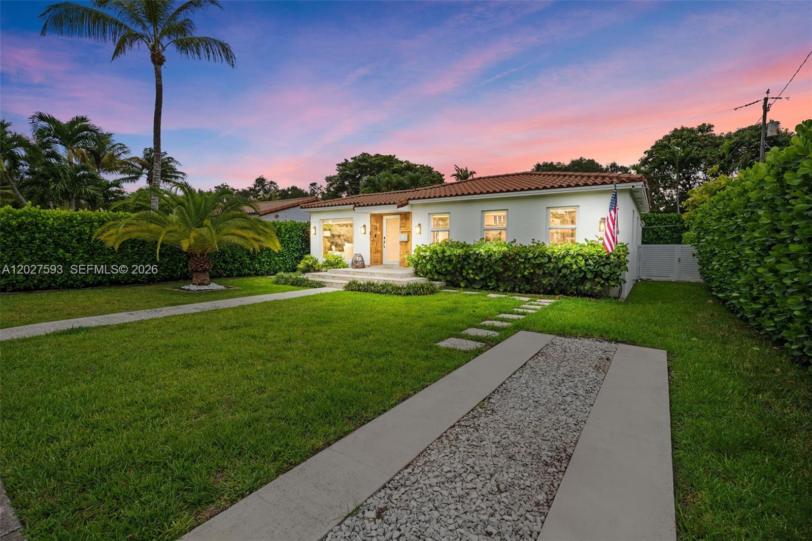 A single-story house with a white exterior, tile roof, and a gravel driveway at sunset — 39 Montilla Ave, Coral Gables FL 33134, CORAL GABLES, FL