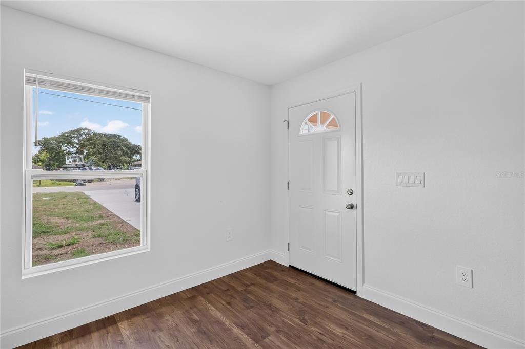 An interior room with white walls, wood-look flooring, a single window, and a white door — 2435 5TH ST NE, WINTER HAVEN, FL