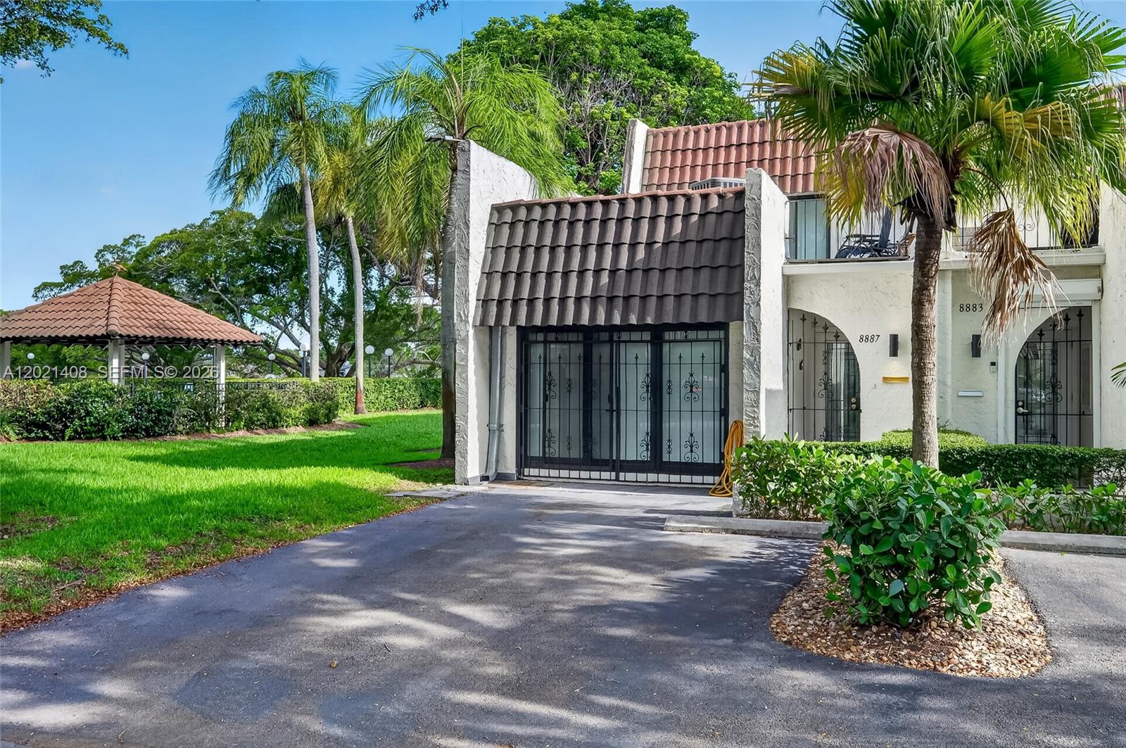 A residential building exterior features a tiled roof, a gated entryway, and a paved driveway — 8887 SW 62nd Ter # A, Miami FL 33173, MIAMI, FL