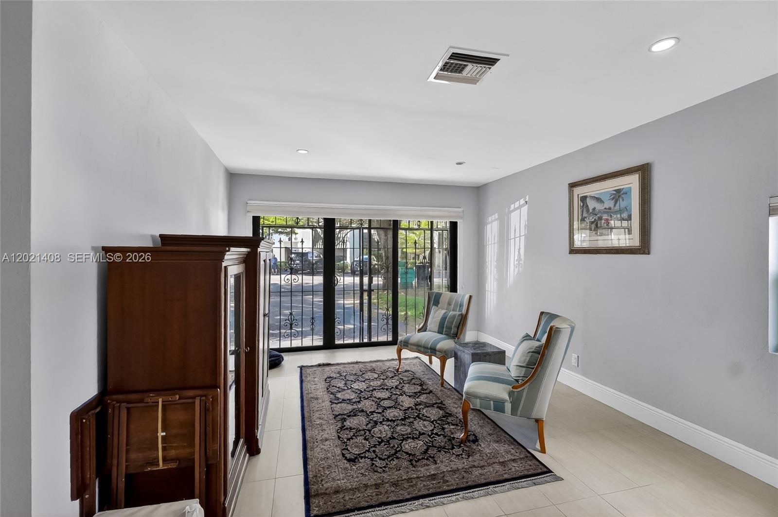 A living area features light tile floors, two striped chairs, a rug, and sliding glass doors — 8887 SW 62nd Ter # A, Miami FL 33173, MIAMI, FL