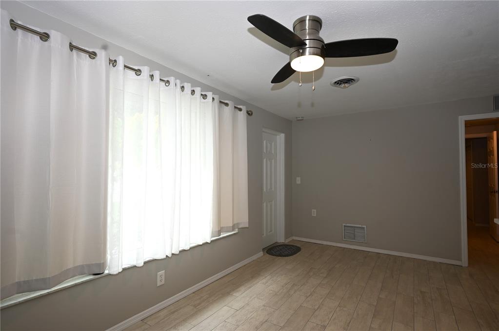 A room with light wood-look tile flooring, gray walls, a ceiling fan, and white curtains — 1620 MORNING DOVE LANE, ENGLEWOOD, FL