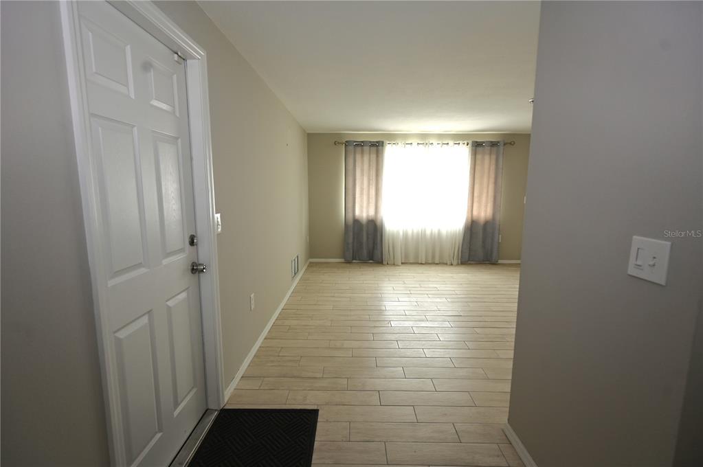 A view of an entryway leading into a living room with light-colored wood-look tile flooring — 1620 MORNING DOVE LANE, ENGLEWOOD, FL