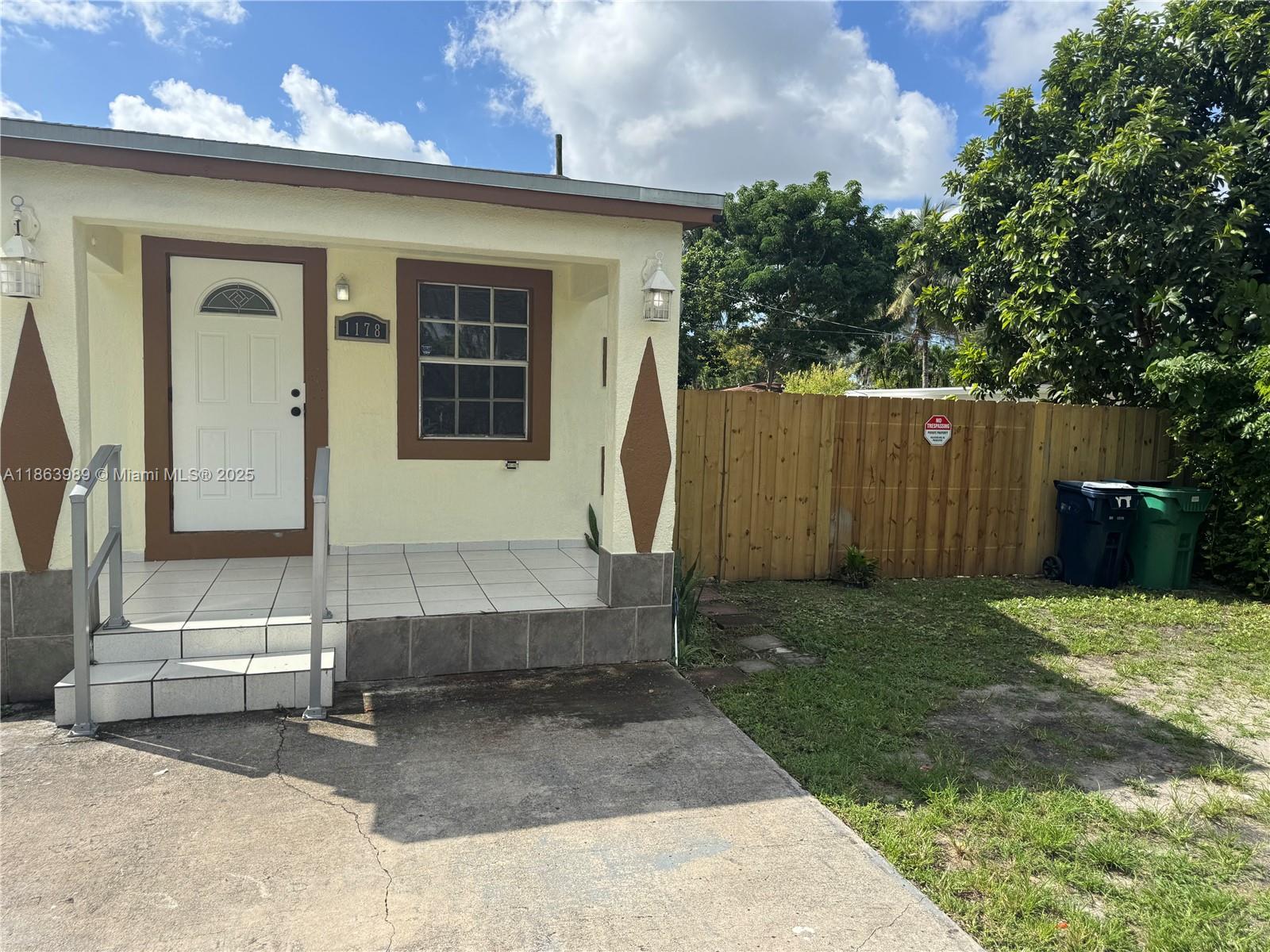 A small, light-yellow house with a tiled front porch and a wooden fence — 1178 NW 105th Ter, Miami FL 33150, MIAMI, FL