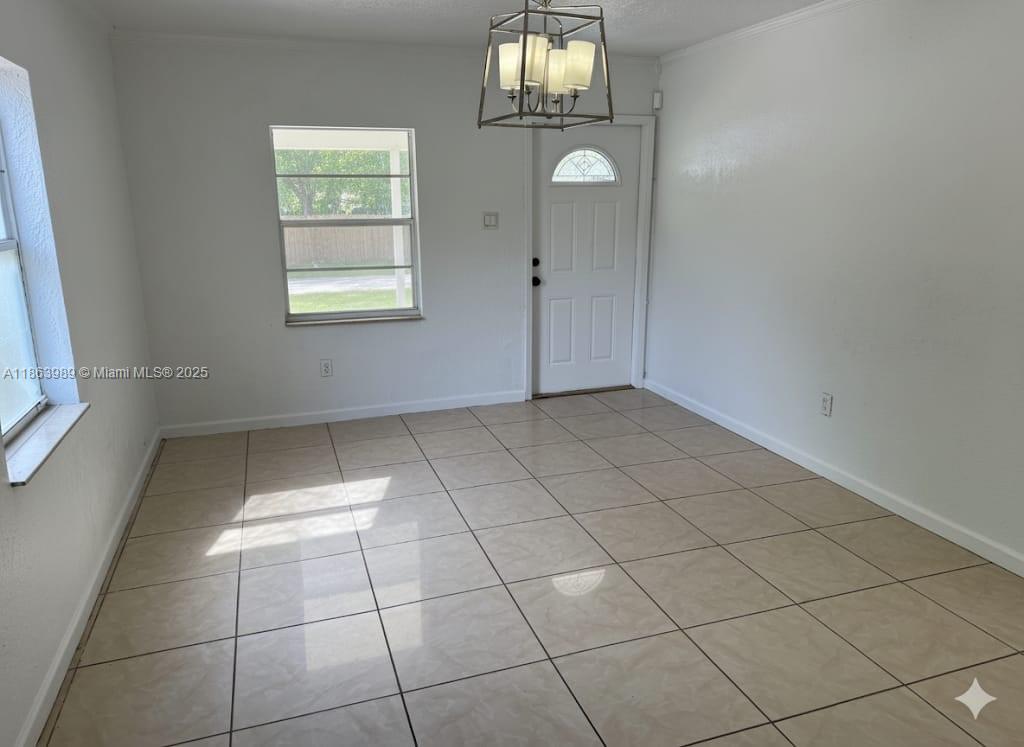 A dining room features beige tile flooring, white walls, a window, and a hanging light fixture — 1178 NW 105th Ter, Miami FL 33150, MIAMI, FL