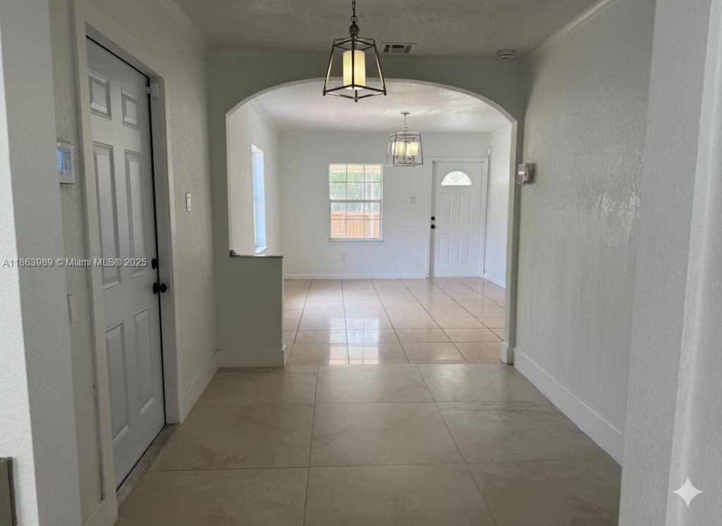 A tiled entryway leads through an arched opening into a bright living area with tile floors — 1178 NW 105th Ter, Miami FL 33150, MIAMI, FL