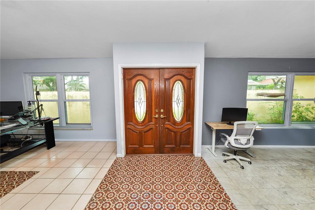 A room with tile flooring, a patterned rug, double wooden doors, and two desk setups — 2010 MOSS COURT, DUNEDIN, FL